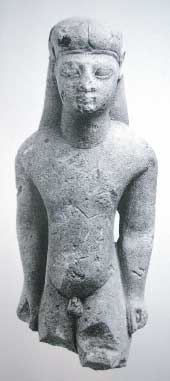 Kouros, voorzijde, een kleine stenen naakte jongen. Het is een votiefgeschenk uit de ori&euml;ntaliserende periode +/- 600 voor Chr., van de Grieken. Omdat het beeldje in Amsterdam te bezichtigen is heeft het de naam &lsquo;de Amsterdamse Kouros&rsquo; gekregen.