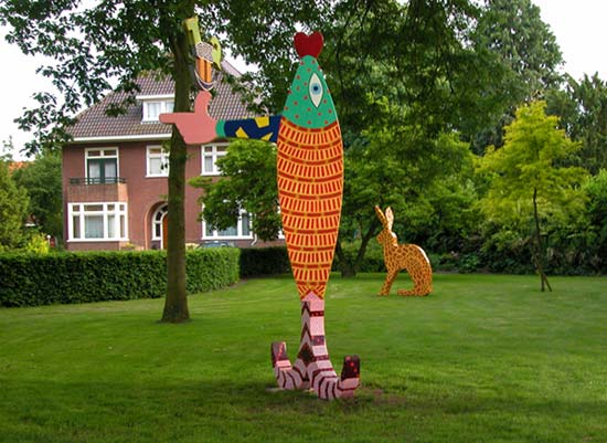 in de pastorietuin op de voorgrond een grote verticale vis getiteld De zalm van lugh. Op de achtergrond een haas met de schutskleuren van een giraf, getiteld Giraf &copy; Andr&eacute; Boone