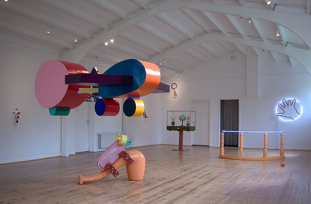 het interieur van de galerie met oa beelden in de vorm van een monumentale gekleurde pijp met hierop een stier, een muziekbox van gekleurde hazen en een boom ingekaderd in een framewerk,&copy;andr&eacute; boone