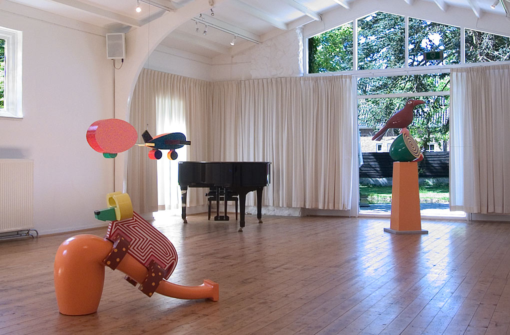 het interieur van de galerie met oa hangend aan het plafond een gekleurde caravan voortgetrokken door een vliegtuig, &copy;andr&eacute; boone 